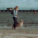 a woman walking her dog on the beach